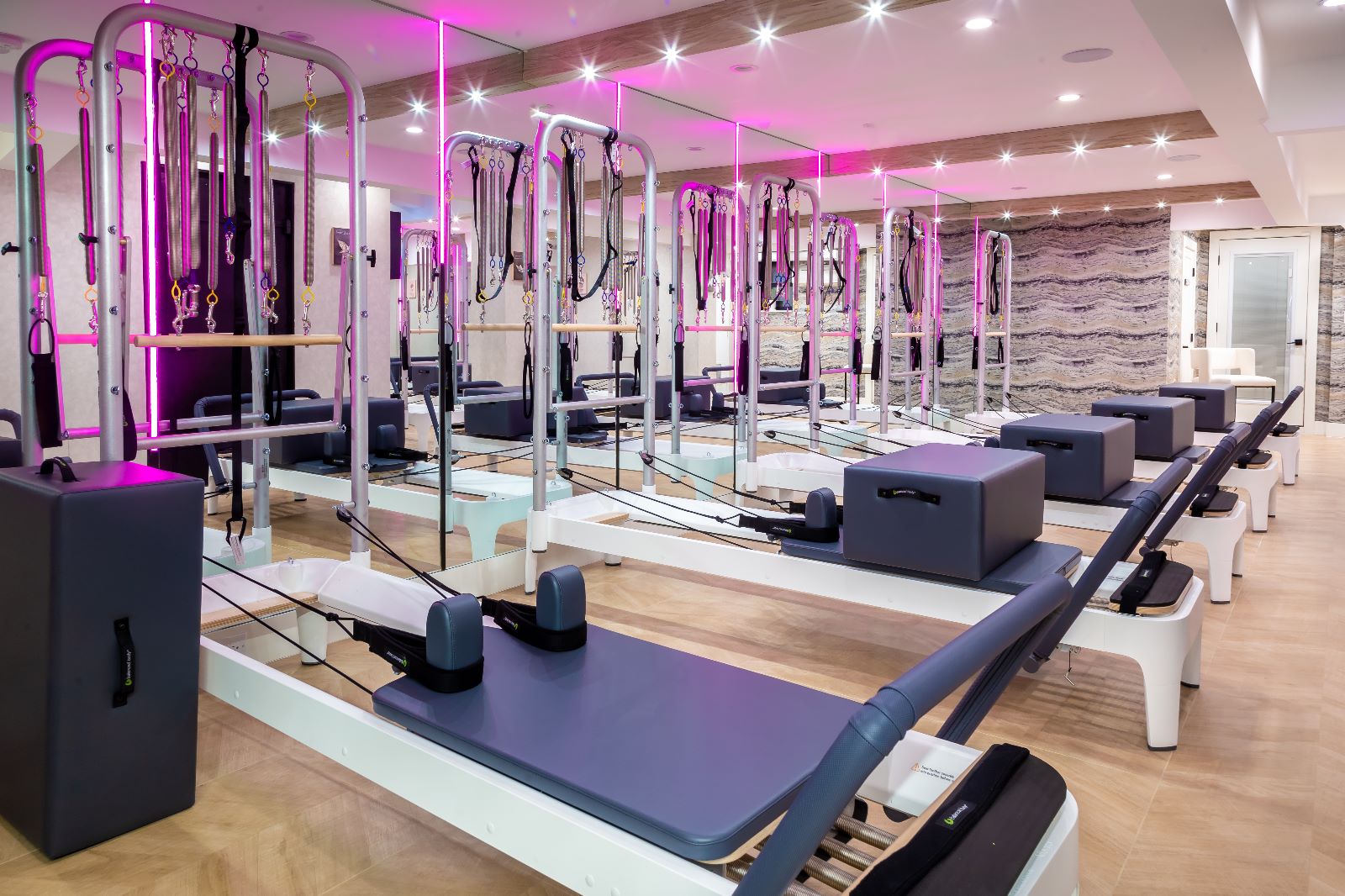The bright Pilates by Mi studio with a row of reformers and purple accents